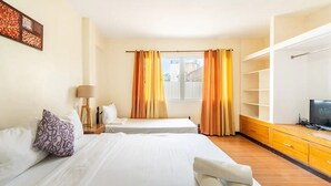 A hotel room with two beds, a TV, a wooden cabinet, and a window with curtains. - WOW! 3BR House w/Karaoke ,Swimming Pool, Pet Friendly (Lapu-Lapu City)