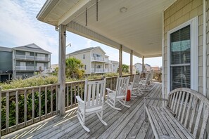 A wooden deck with white rocking chairs and a covered area with a railing. - Port Folio - Adorable 3 BR home with Covered Porch! (Surf City)