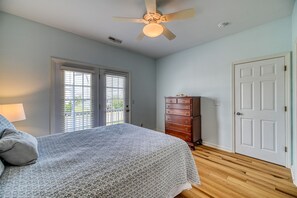 Une chambre à coucher avec un lit, une commode, un ventilateur de plafond et une porte.