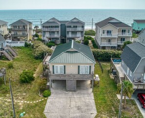 A residential area with houses, a concrete driveway, and a view of the ocean. - Port Folio - Adorable 3 BR home with Covered Porch! (Surf City)