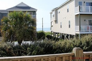 A beachfront property with a two-story building, a balcony, and a palm tree. - Port Folio - Adorable 3 BR home with Covered Porch! (Surf City)
