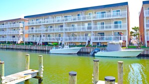 A waterfront hotel with multiple balconies, a dock, and boats. - The Chateau 101B-Baywater 9thth St, W/D, AC, Free WIFI (Ocean City)