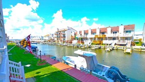 A marina with boats docked, a flag, and a row of buildings with balconies. - The Chateau 101B-Baywater 9thth St, W/D, AC, Free WIFI (Ocean City)