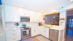 A modern kitchen with white cabinetry, stainless steel appliances, and a central island. - The Chateau 101B-Baywater 9thth St, W/D, AC, Free WIFI (Ocean City)
