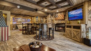 A rustic bar area with wooden beams, stone walls, and a television mounted on the wall. - Fabulous Private Pool with Waterfall! Tudor Rose Lodge (Sevierville)