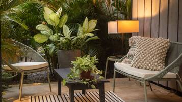 A patio area with wicker furniture, a table, and a potted plant.