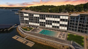 A modern hotel with a rooftop pool, a dock, and a view of the water and trees. - Brand New Complex, Central Location, Amazing Views (Osage Beach)