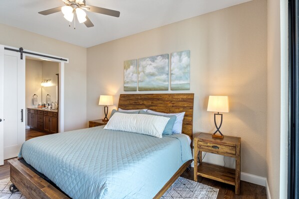 A bedroom with a bed, wooden headboard, nightstands, and a ceiling fan.