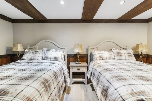 Habitación doble con cama, techo de madera y dos mesitas de noche con lámparas.