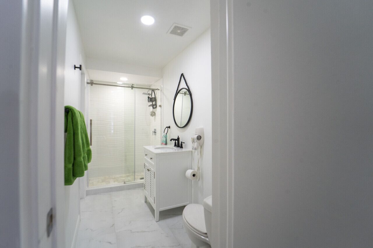A bathroom with a glass shower, white sink, and toilet.