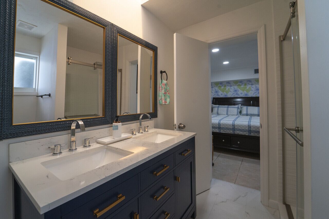 A bathroom with a double sink, a large mirror, and a shower area.