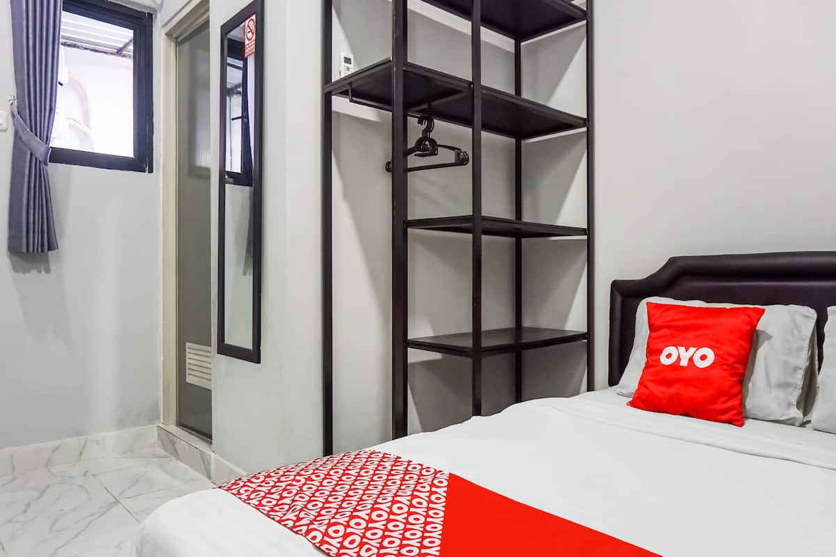 A hotel room with a bed, a wardrobe, and a mirror.