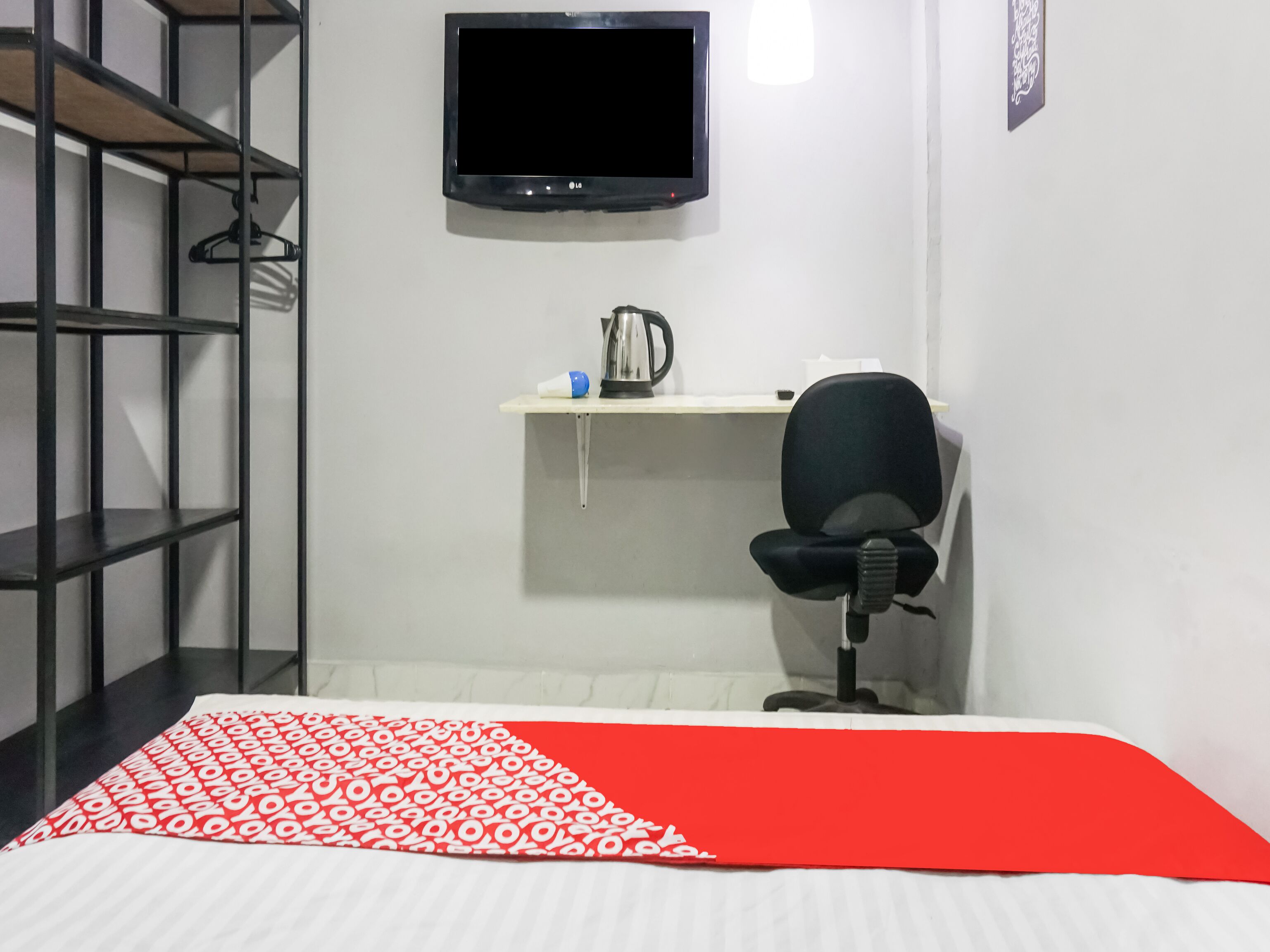 Une pièce comprenant un lit, un bureau avec une chaise, un téléviseur et une étagère.