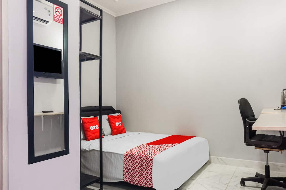 A compact hotel room with a bed, a desk, and a chair.