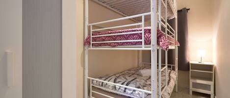 Quarto com beliche, escrivaninha e luminária.