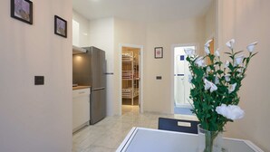 A modern kitchen with a built-in refrigerator, a dining area with a table and chairs, and a hallway leading to a bedroom with a bunk bed. - Tejares 16, Apartment 2 bedrooms Ground Floor (Sevilla)