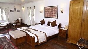 Ein traditionell eingerichtetes Zimmer mit einem Holzbett, einem kleinen Tisch, einem Stuhl, einem Kleiderschrank und einem großen Teppich.