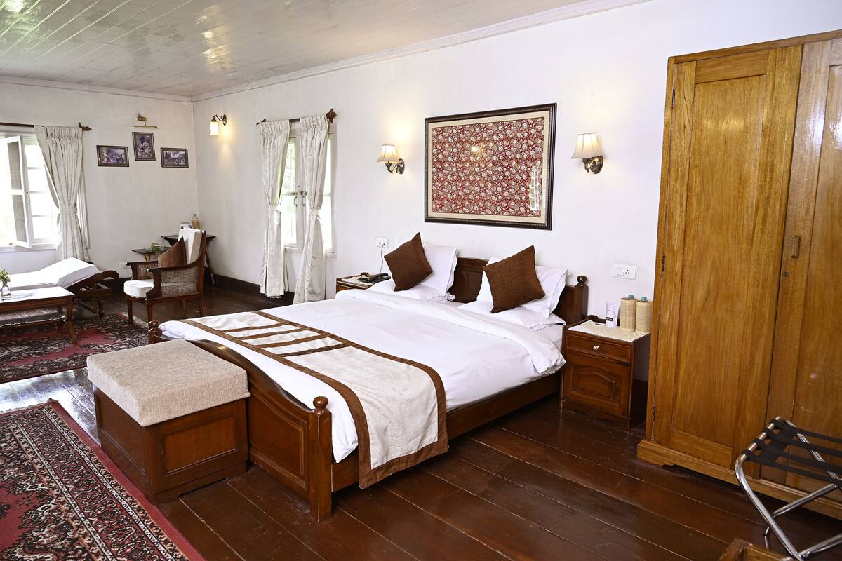A traditional room with a wooden bed, a small table, a chair, a wardrobe, and a large rug.