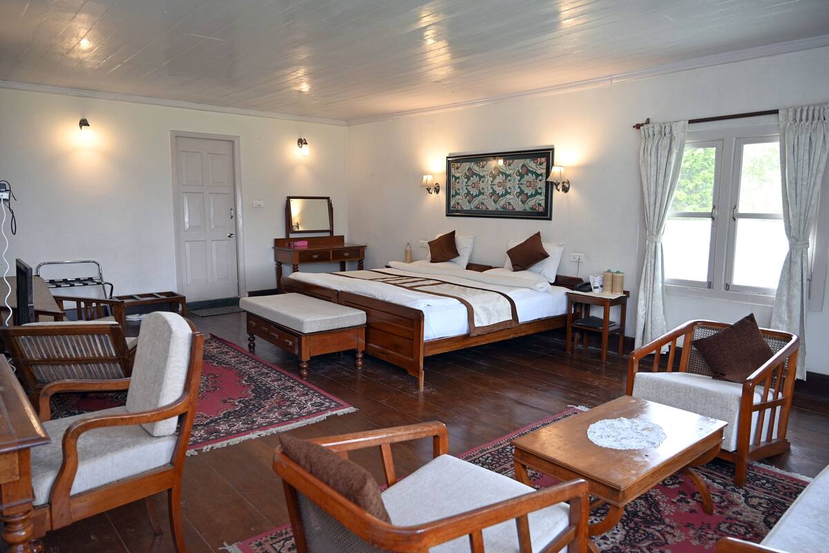 A spacious room with a large bed, wooden furniture, a rug, and a painting on the wall.