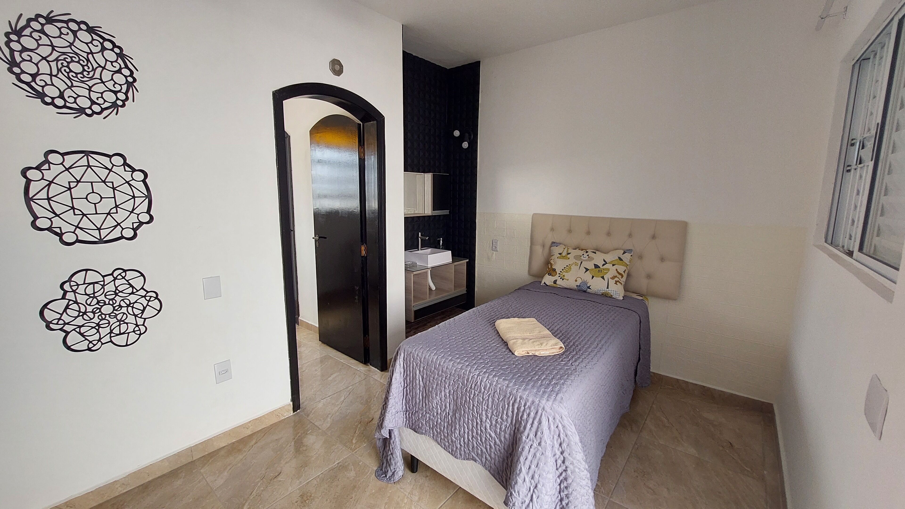 A bedroom with a bed, a nightstand, a dresser, a mirror, and decorative wall art.