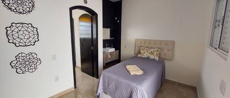 A bedroom with a bed, a nightstand, a dresser, a mirror, and decorative wall art.
