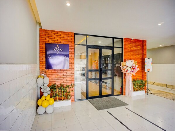 A hotel entrance with a brick facade, a glass door, and a signboard.