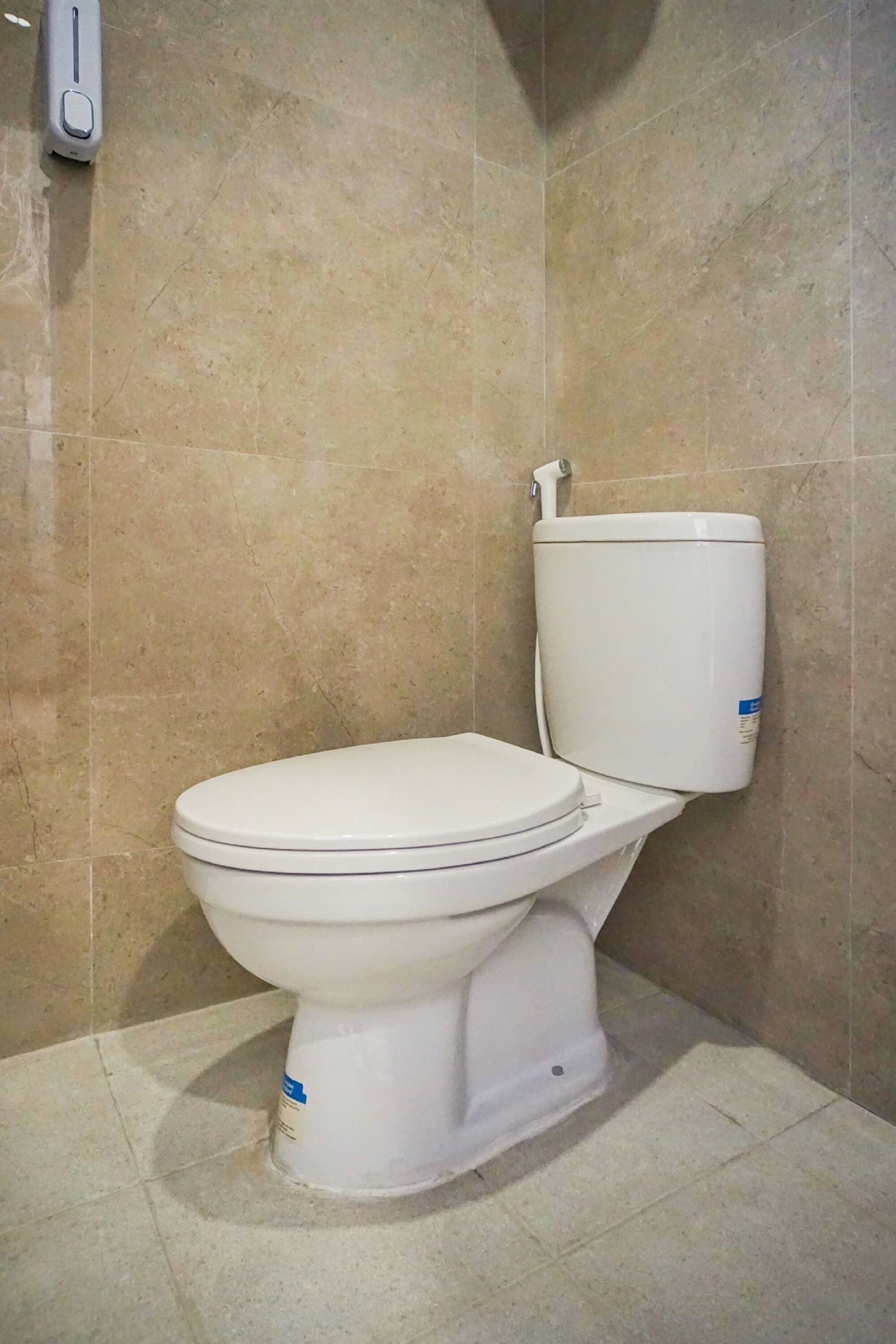 A standard white toilet in a bathroom with beige tiles.