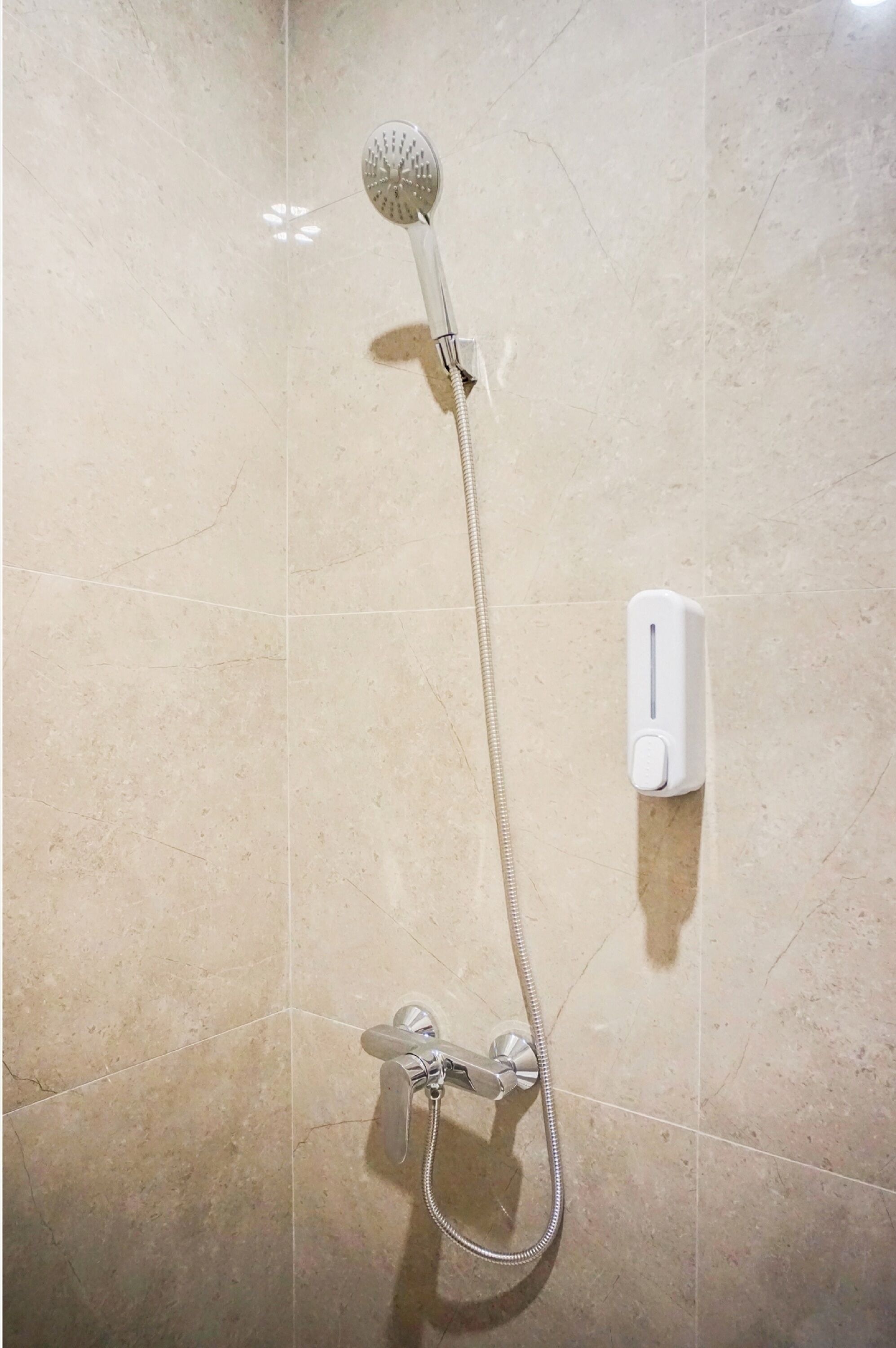 Une douche équipée d’un pommeau de douche à main et de commandes murales.