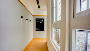 A hallway with a wooden floor, white walls, and a sign indicating room 3A. - Hotel O Alhesa Residence (Medan)