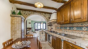 A kitchen with wooden cabinets, a tiled backsplash, and a stone archway.