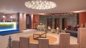 A modern lobby with a reception desk, a stone fireplace, and a round seating area. - Wifi, ski-in/ski-out & foot of the slopes, swimming pool, sauna, hammam, balcony, tv, ski locker (Val Thorens)
