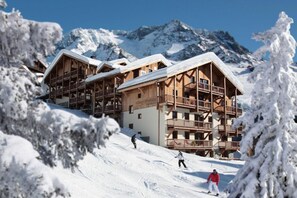 A wooden chalet-style building with multiple balconies and a sign reading "Village Montana."