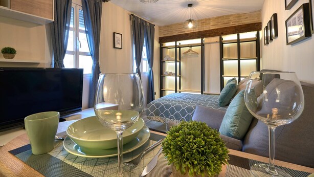 A modern hotel room with a bed, seating area, and a TV. - Castilla 75, Urban Loft 1st floor (Sevilla)