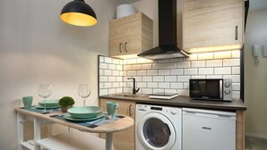 A compact kitchen with a washing machine, a microwave, and a sink. - Castilla 75, Urban Loft 1st floor (Sevilla)