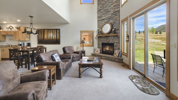 A spacious living room with a fireplace, a dining area, and a kitchen. - Overlooks 9th Green | Discount Golf Privileges | Golf & Ski (South Fork)
