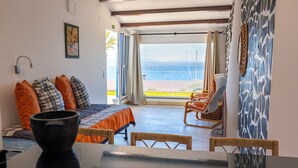 Une chambre à coucher avec un lit, une chaise, une table et une vue sur la mer, visible à travers une grande fenêtre.