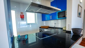 Une cuisine moderne avec un plan de travail noir, des armoires bleues et une hotte de cuisine en acier inoxydable.