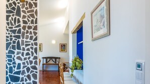 Un couloir avec un plancher en bois, un mur en pierre, une porte bleue et un tableau encadré accroché au mur.
