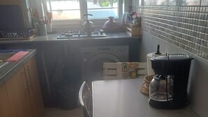 A kitchen with a table, chairs, a stove, and a window. - Super et Nouvel Appart Proche de la Plage (Skhirat)