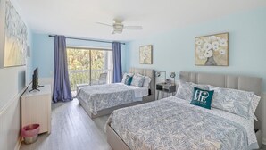Ein Schlafzimmer mit zwei Betten, einem Deckenventilator, einem Fernseher und Bildern an den Wänden.