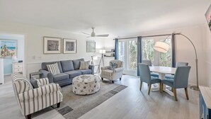 Ein modernes Wohnzimmer mit einer Couch, Sesseln, einem Esstisch und einem Deckenventilator.