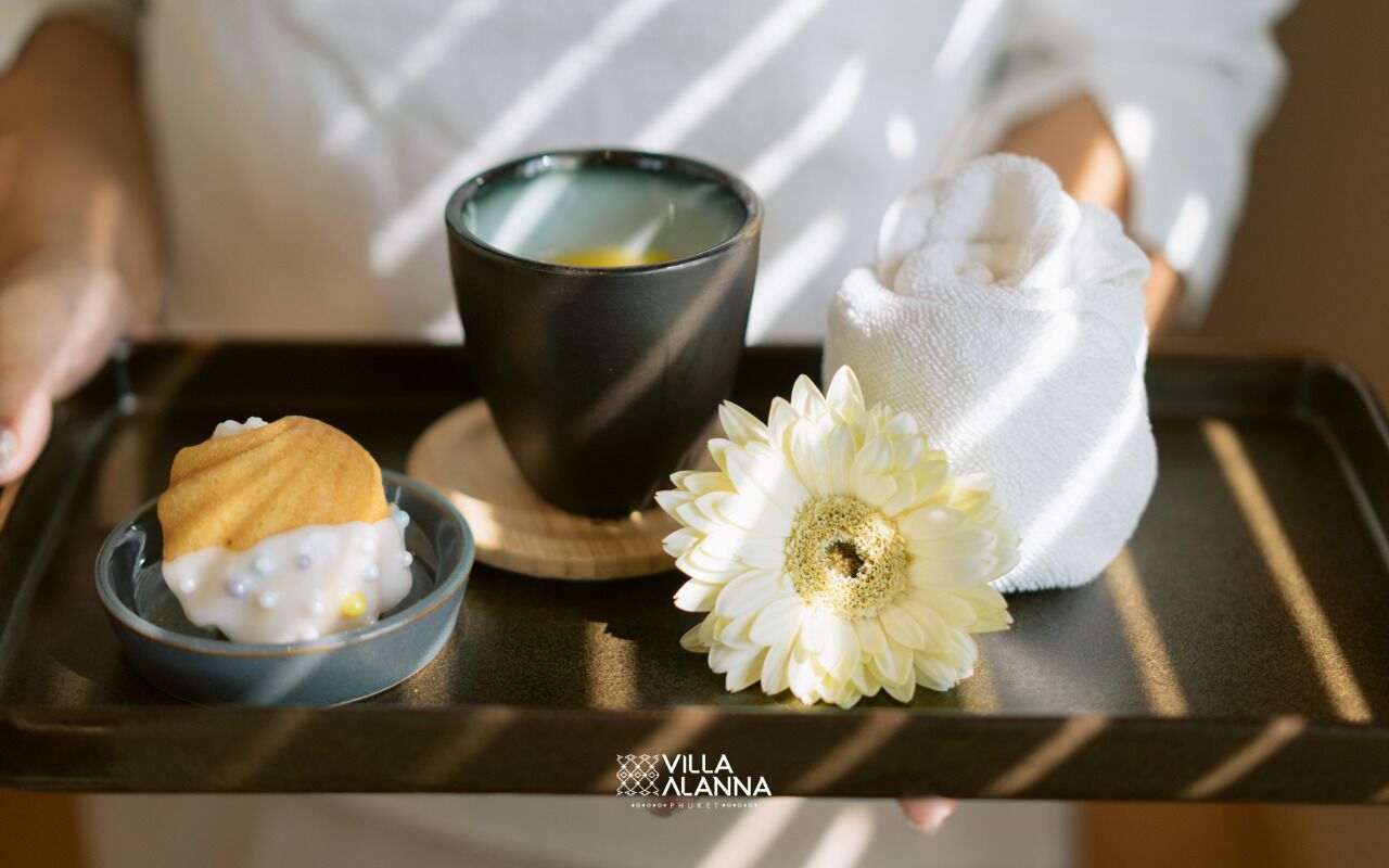 A tray with a candle, a flower, and a dessert.