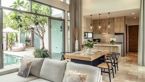 Una cocina moderna con una isla central, ventanas amplias y un comedor con sofá y sillas.