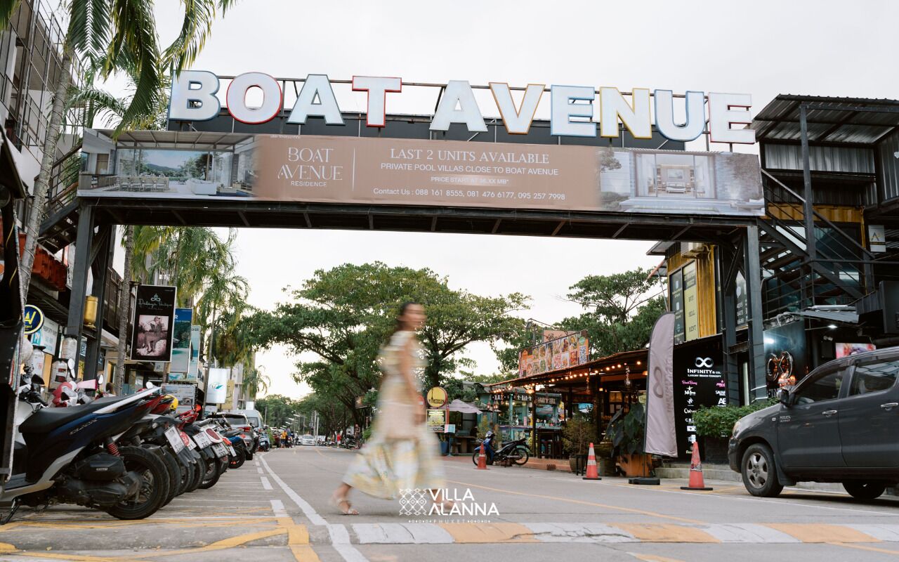 A street view with a sign for 'Boat Avenue' indicating a residential area. There are parked motorcycles and a pedestrian crossing the street.