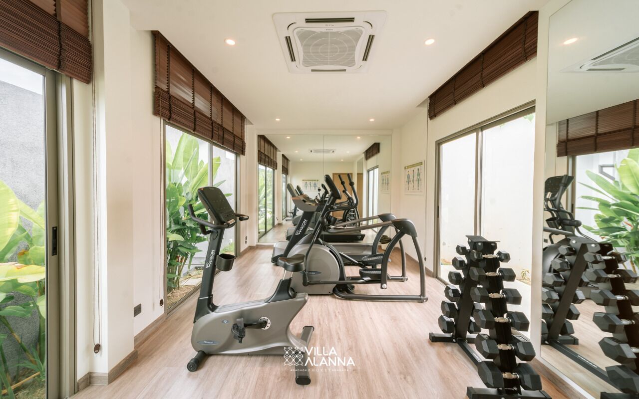 A gym with exercise equipment, large windows, and a mirrored wall.