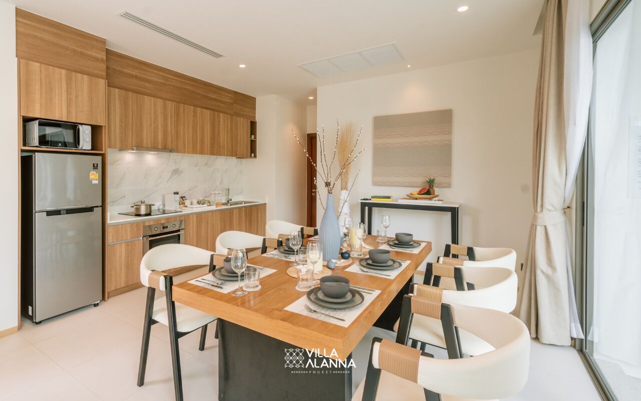 A modern kitchen with wooden cabinets, a stainless steel refrigerator, and a dining area with a wooden table set for four.