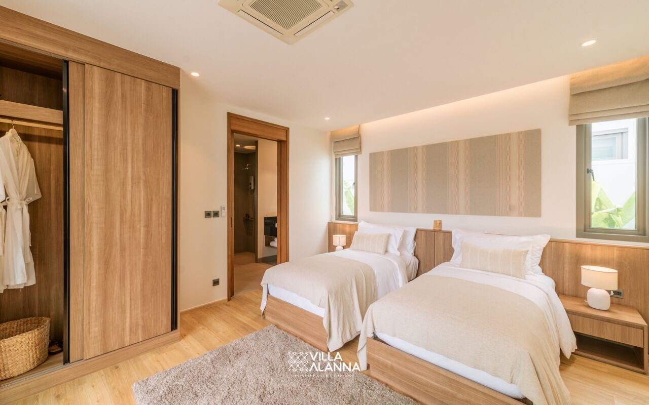 Een slaapkamer met twee bedden, een houten garderobe en een groot raam.