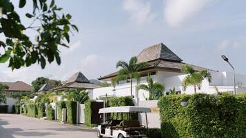 A row of modern villas with sloped roofs, surrounded by well-maintained hedges and palm trees.