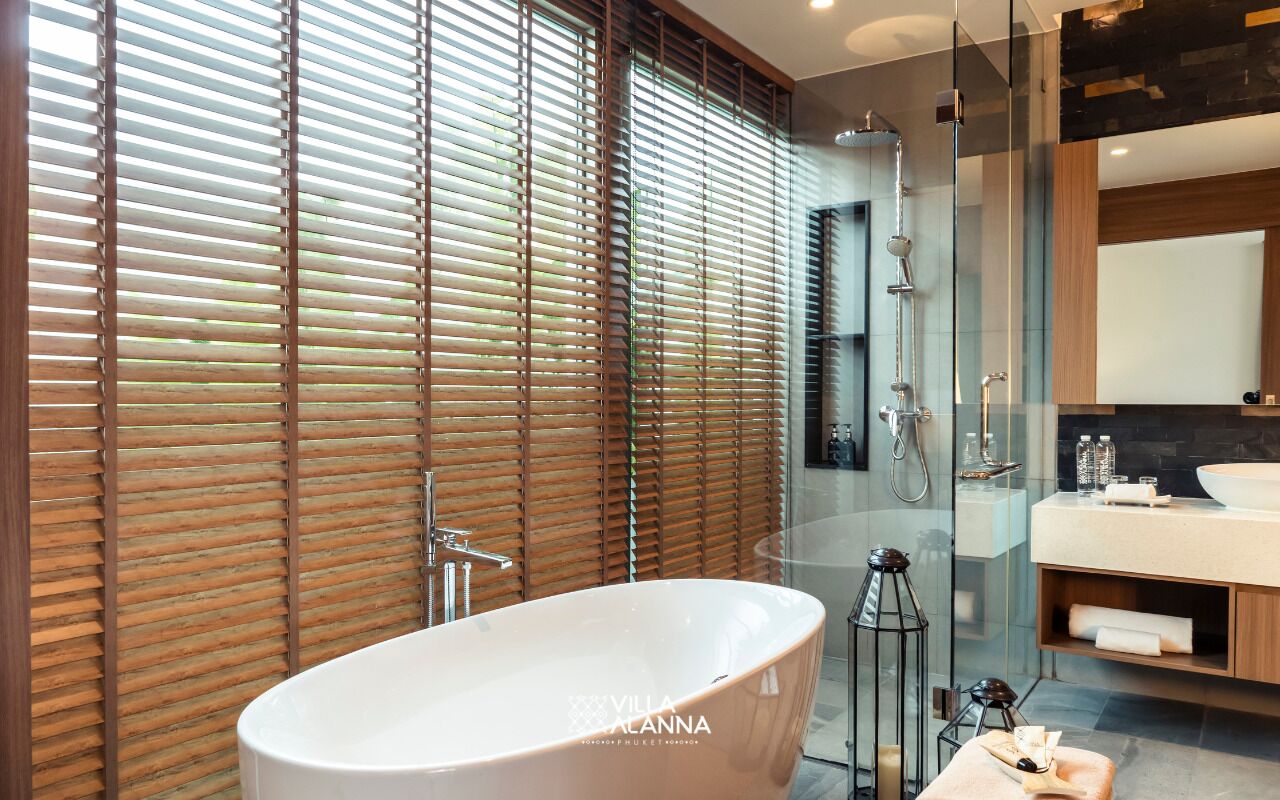 Un baño moderno con una bañera independiente, cabina de ducha de vidrio y puerta corredera de madera.