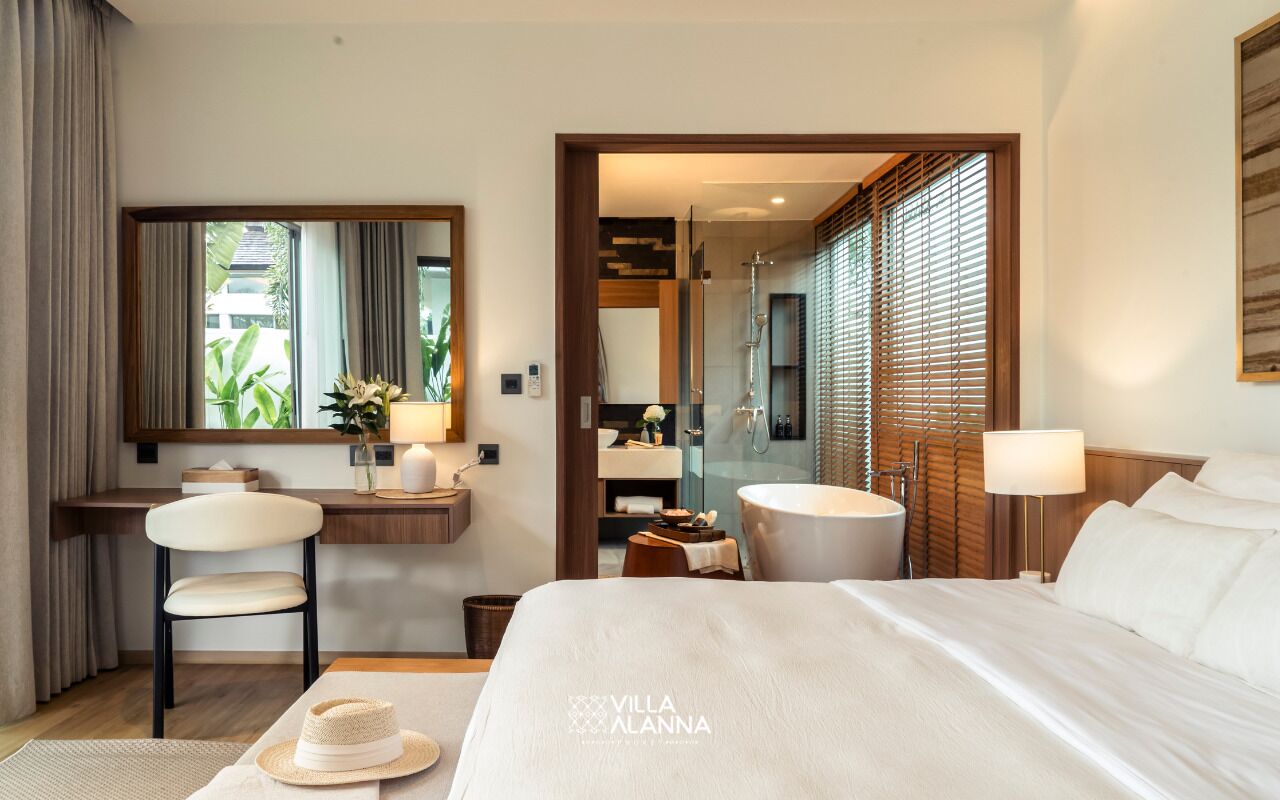 Une chambre d’hôtel comprenant un lit, un bureau, une chaise, une coiffeuse avec un miroir, et une salle de bain avec douche et toilettes.